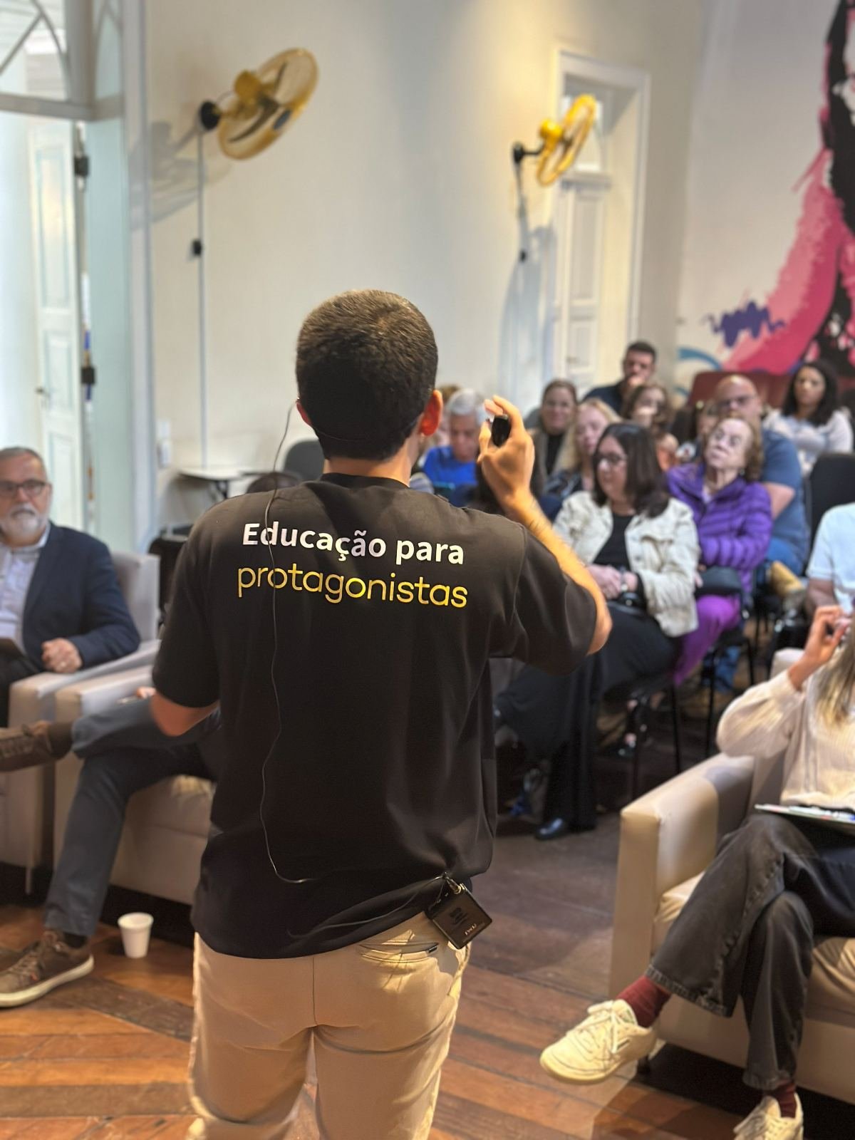 Facilitador do Trilhar Labs no palco do DemoDay, de frente para pais e diretores