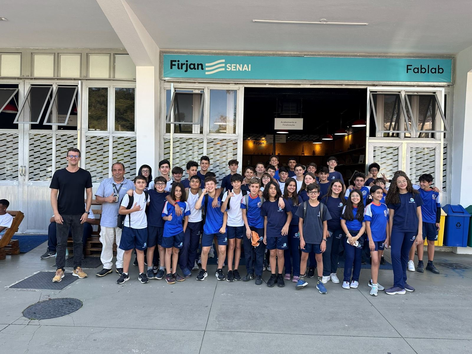 A group of students at the entrance of the Firjan SENAI Fab Lab on Trilhar Day